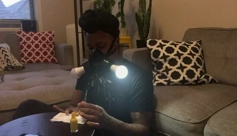 person wearing a light up gas mask while painting nails